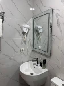 Un baño blanco con lavabo y espejo. en Hotel Elegant 2, en Andizhan 27 fotos más