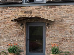 a brick building with a black door and flowers at Blaenau - Uk50400 in Llanstephan