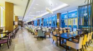 ein Esszimmer mit Tischen und Stühlen und Fenstern in der Unterkunft Xincheng hotel in Zunyi