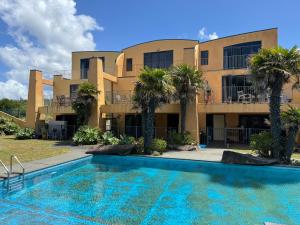 a villa with a swimming pool in front of a building at La Belle Maison - Ruakaka Holiday Apartment in Ruakaka