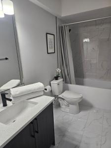 a white bathroom with a toilet and a sink at Cozy on Baywater in Airdrie