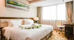 a hotel room with a large white bed with flowers on it at Xingtai Yuehai Hotel in Haikou