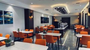 ein Esszimmer mit Tischen und orangefarbenen Stühlen in der Unterkunft GreenTree Inn Express Datong High-Speed Railway Station Wanda Plaza Fangte in Shuiposhi
