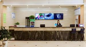 Eine Frau, die an einer Bar in einer Lobby sitzt. in der Unterkunft GreenTree Alliance Hotel Yancheng Engineering College Dayangwan Scenic Area in Ti-pa-yung