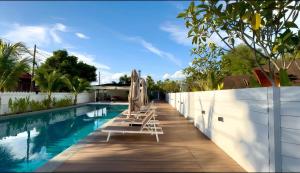 a swimming pool with chairs next to a white fence at Found Mansion Langkawi in Pantai Cenang