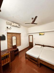 a bedroom with a bed and a desk and a ceiling fan at devanjana inn in Jāmb