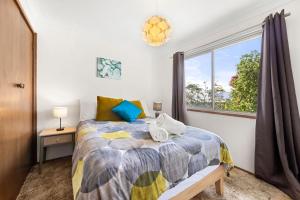 un dormitorio con una cama y una ventana en Sandpiper at Jervis Bay - Rustic Retreat, en Callala Beach