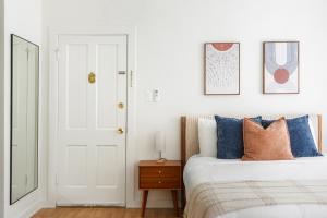 een witte slaapkamer met een bed met blauwe kussens bij Beverly Grove Hotel in Los Angeles