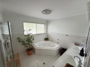 a white bathroom with a tub and a sink at Palacete Beach Resort in Culburra Beach