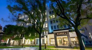 un grand bâtiment blanc avec des arbres devant lui dans l'établissement Vienna Hotel Wuhan Guobo Jiangang Metro Station, à Wuhan