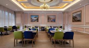 a dining room with tables and chairs and a chandelier at Vienna Hotel Jiangsu Zhangjiagang Passenger Terminal Station in Zhangjiagang