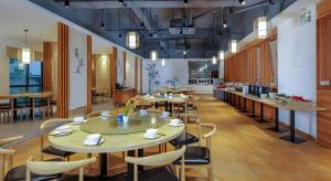a large room with tables and chairs and a kitchen at Vienna Hotel Zhuhai Huafashangdu Nanping Science Industrial Park in Nanping