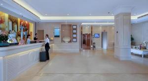 a woman standing at a counter in a hotel lobby at Vienna Hotel Zhuhai Huafashangdu Nanping Science Industrial Park in Nanping