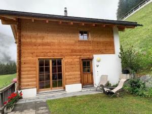 une petite maison en bois avec deux chaises devant elle dans l'établissement Neuwertiges 2 Zi Ferienchalet 55M2, à Monstein