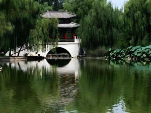 eine Brücke über einen Teich in einem Park in der Unterkunft Gya Hotel Beijing Shunyi Yanjing Bridge in Shunyi
