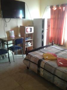 una camera da letto con un letto, un tavolo e una televisione di Alquimia a Capilla del Monte