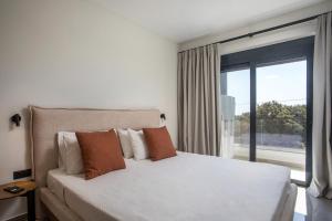 Un dormitorio con una cama blanca y una ventana grande. en Rodos Nest with terrace and seaview, en Asgourou