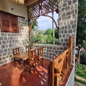 une table et des chaises en bois sur une terrasse avec une fenêtre dans l'établissement G&J House - Bulle tropicale, à Andilana