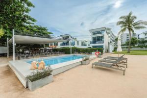 a swimming pool with two benches and a building at C245 Steps from the Beach Pool & Ocean View in Ban Saiyuan (1)