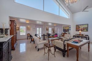 - un grand salon avec des canapés et des chaises dans l'établissement SaffronStays Brunton House, Alibaug - luxury pool villa near Awas Beach, à Alibaug