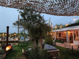 eine Terrasse mit einem Baum und Tischen sowie ein Gebäude in der Unterkunft Comfortable holiday home in Noordwijkerhout near the sea in Noordwijkerhout + 33 Fotos