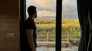 Una mujer mirando desde una ventana hacia un viñedo. en Monteleone X by Tiny Away, en Battipaglia