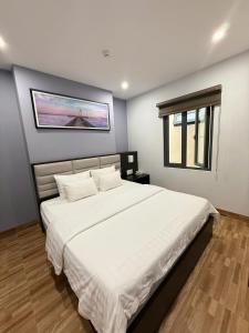 une chambre avec un grand lit blanc avec un tableau sur le mur dans l'établissement Novelty Hotel, à Vung Tau