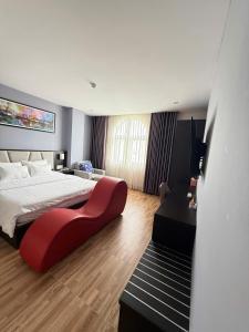 une chambre avec un grand lit et une chaise rouge dans l'établissement Novelty Hotel, à Vung Tau