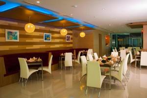 ein Restaurant mit Tischen und weißen Stühlen und Lichtern in der Unterkunft V-One Hotel Korat in Ban Khok Phai (1)