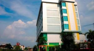 ein hohes weißes Gebäude mit einer Palme davor in der Unterkunft V-One Hotel Korat in Ban Khok Phai (1)