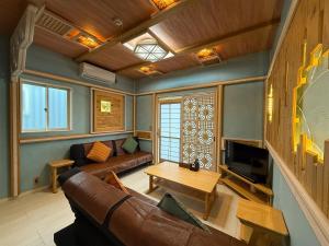 a living room with a couch and a tv at Yufuin Onsen 8A1 Yaeichi in Yufuin