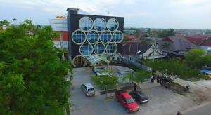 ein Gebäude mit auf einem Parkplatz geparkten Autos in der Unterkunft Fovere Hotel Palangkaraya in Palangkaraya