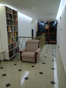 ein Wohnzimmer mit einem Stuhl und Bücherregalen in der Unterkunft APARTMANSKI SMEŠTAJ SOLARIS kod Aqua Parka Yuth Studio in Sokobanja