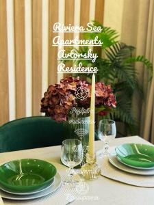 a table with green plates and a candle and flowers at Riviera Sea Apartments Avtorsky Residence in Fontanka