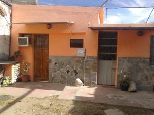 una casa arancione con una porta di legno e un edificio di Alquimia a Capilla del Monte