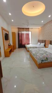 a large room with two beds and a television at Hotel Pilgrim Near Golden Temple in Amritsar