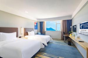 ein Hotelzimmer mit zwei Betten und einem Schreibtisch in der Unterkunft Holiday Inn Express Zhangye By IHG in Zhangye + 36 Fotos