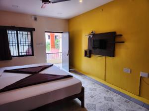 Un dormitorio con una cama y un televisor en la pared. en SKT's Wisteria Inn, en Yercaud