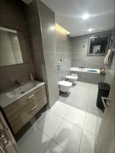 a bathroom with a sink and a toilet and a tub at Grand appartement 3 chambres à la résidence valmascort Annaba in Annaba