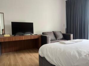 a hotel room with a bed and a tv and a couch at J&P Hotel Sriracha in Ban Hua Na