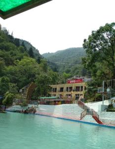 une grande masse d'eau avec un bâtiment en arrière-plan dans l'établissement Kempty Lake Waterfall Resort - Run by Anaysha Group, à Mussoorie