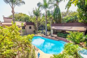 an exterior view of a house with a swimming pool and trees at Guesthouse Charis in Pretoria