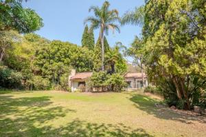 a house in the middle of a yard with trees at Guesthouse Charis in Pretoria
