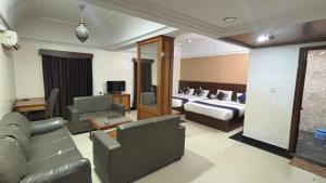 a hotel room with a bed and a couch at Hotel Chetan International in Bangalore