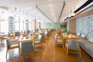 a restaurant with wooden tables and chairs and windows at Warmly Hotel Suzhou Shuanghuwan in Suzhou