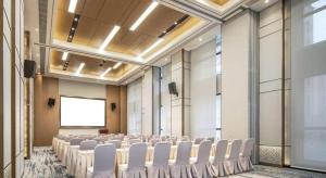 Zimmer mit weißen Stühlen und einem Bildschirm in der Unterkunft Metropolo Hotel Yining Development Zone Hanma Building in Yining Airport