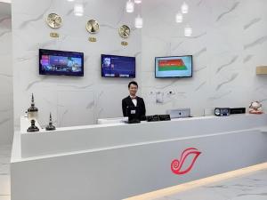 un hombre parado detrás de un mostrador en una tienda en Shell Shanghai Songjiang District Xinqiao Town Xinqiao Hotel, en Chunshen