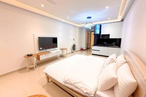 une chambre blanche avec un grand lit et une télévision à écran plat dans l'établissement Luxury Studio at Monal Murree Balcony with Private Parking, à Murree