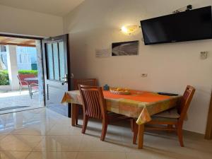 a dining room table with chairs and a television on the wall at Apartments Magdalena - Bungalow with terrace A1 in Bol