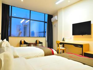 a hotel room with two beds and a desk with a television at Thank Hotel Jiangxi Jiujiang Lianxi District Railway Station Square in Jiujiang